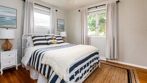 Une chambre à coucher avec un lit, des tables de chevet, un ventilateur de plafond et une fenêtre avec des rideaux.
