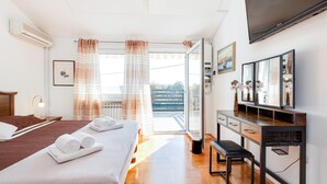 Habitación de hotel con cama, escritorio, silla, televisión y vistas al exterior.