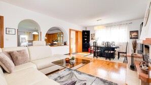 Una sala de estar moderna con un sofá, una mesa de centro de vidrio y un comedor con sillas y una mesa.