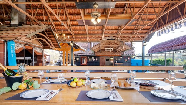 Un comedor con mesas de madera, un ventilador de techo y vistas al exterior.