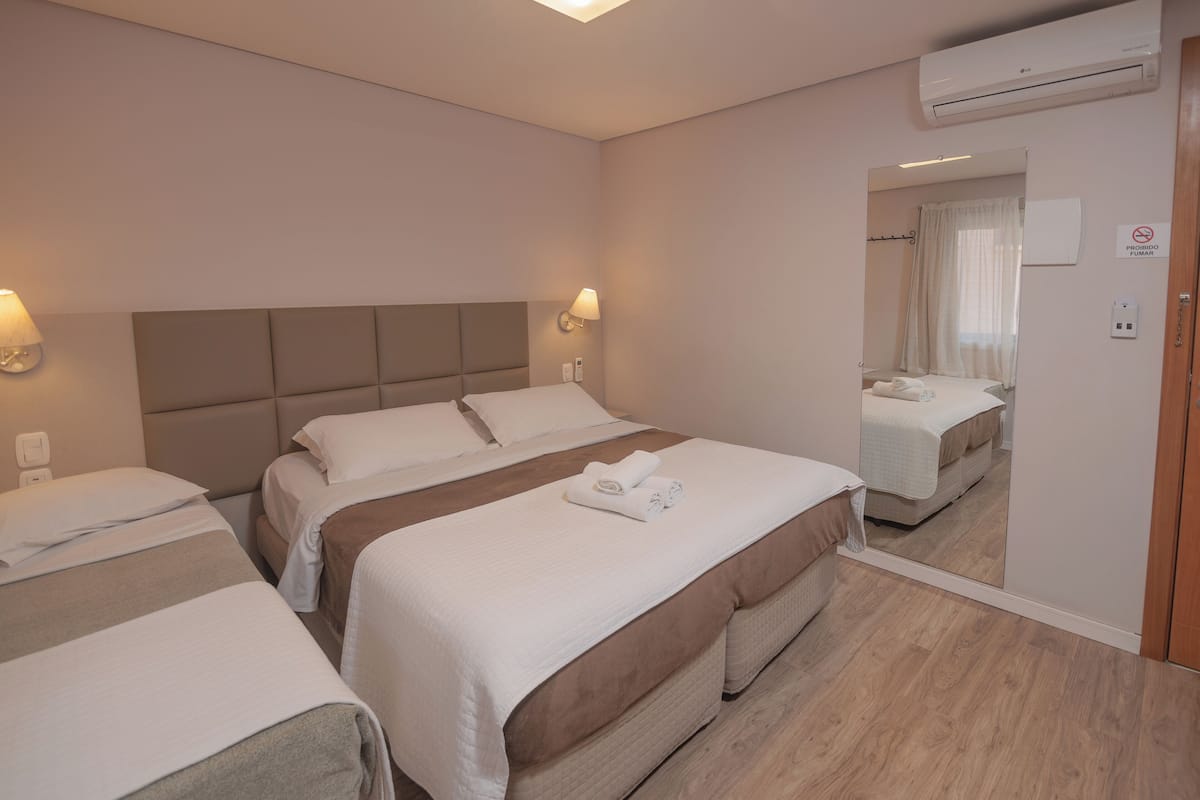A hotel room with two beds, a large mirror, and an air conditioning unit.