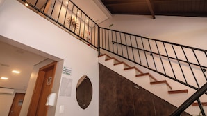 Una scala con ringhiera in legno e corrimano in metallo nero, che conduce a un piano superiore.