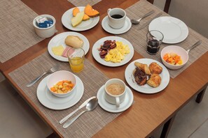 A breakfast table with plates of food, cups, and cutlery. - Pousada Zammá Gramado (Gramado)