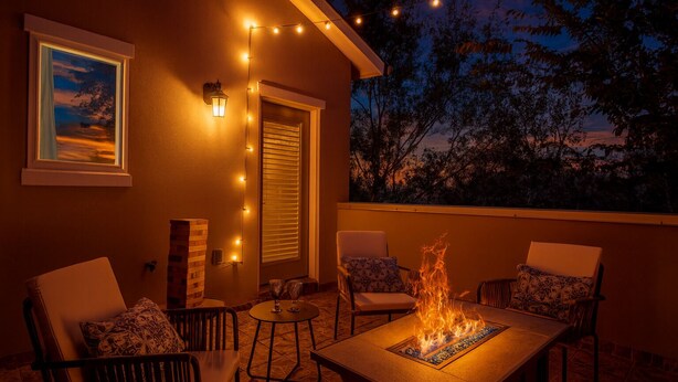 An outdoor patio with a fire feature, chairs, a table, string lights, and a framed picture on the wall. - Cozy retreat 5 Min from Downtown Houston 4bd - Rooftop Views !! (Houston)