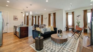A modern living room with a dark blue sofa, a round coffee table, and a dining area with a wooden table and chairs. - Cozy retreat 5 Min from Downtown Houston 4bd - Rooftop Views !! (Houston)