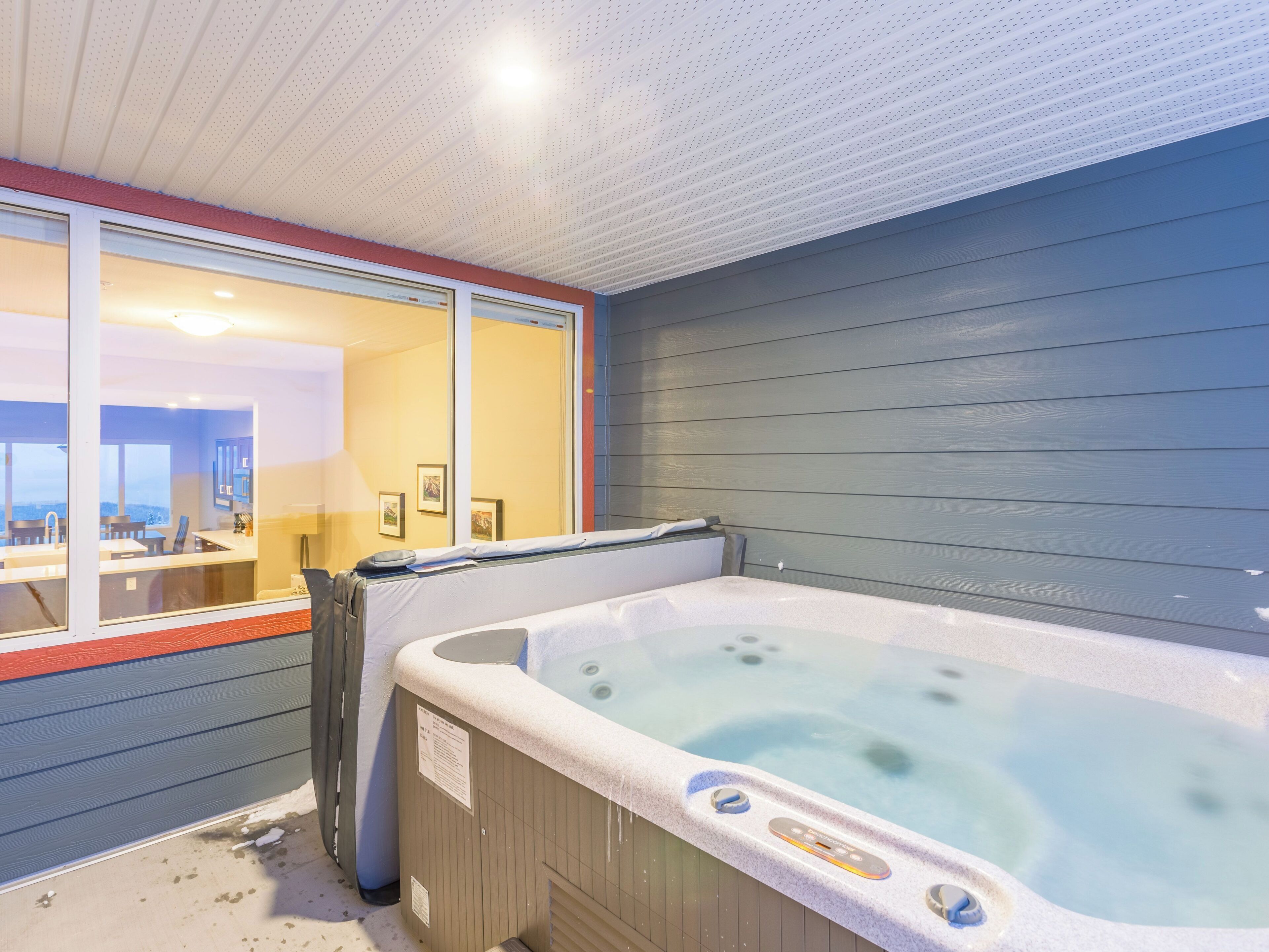 A bathroom with a hot tub, a window, and a mirror.