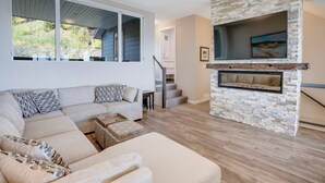 Ein modernes Wohnzimmer mit einer Eckcouch, einem Kamin und einer Treppe zu einer oberen Ebene.