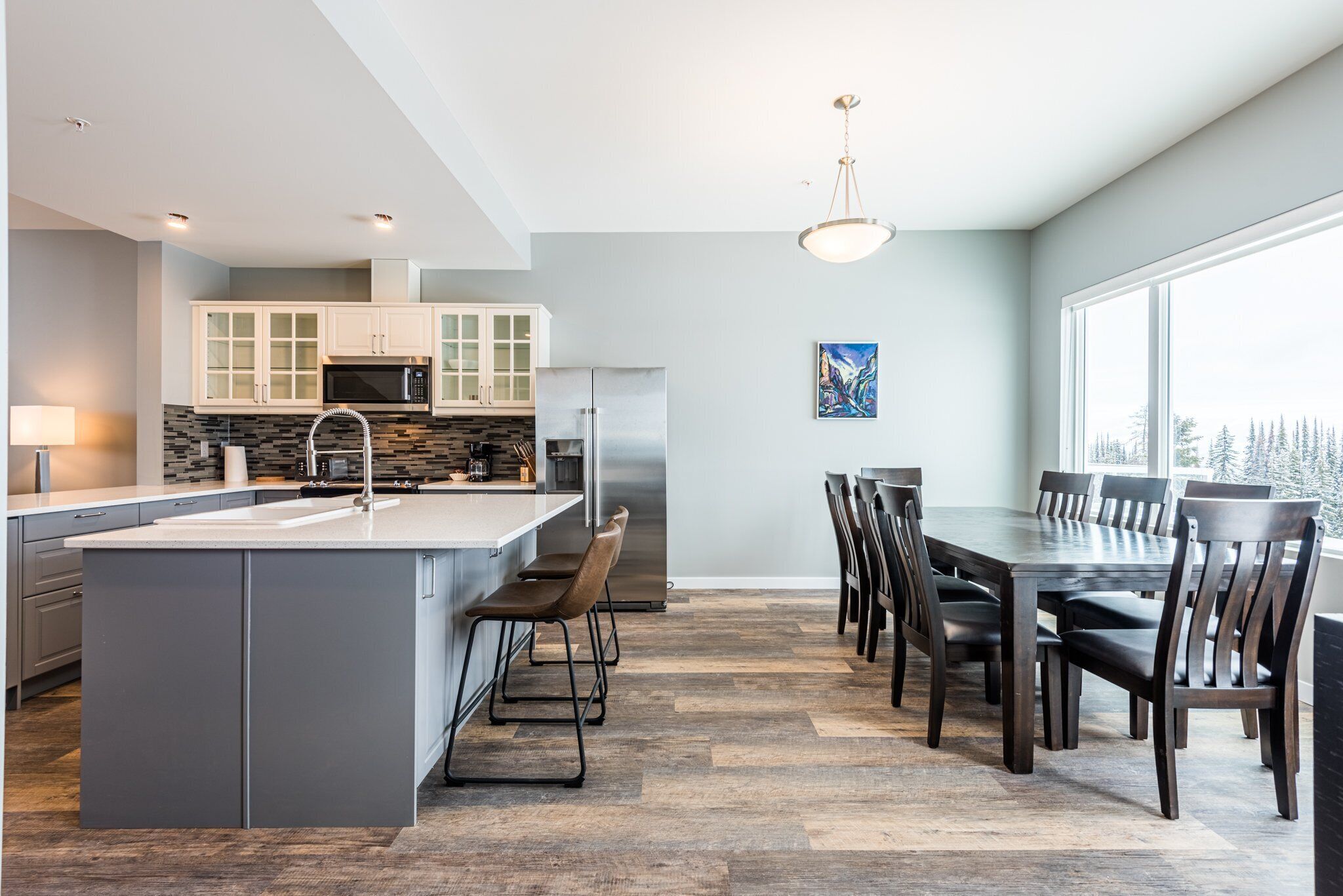 A modern kitchen with a central island, built-in appliances, and a dining area with a large table and chairs.