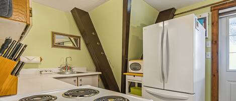 A kitchen with a stove, refrigerator, and sink.