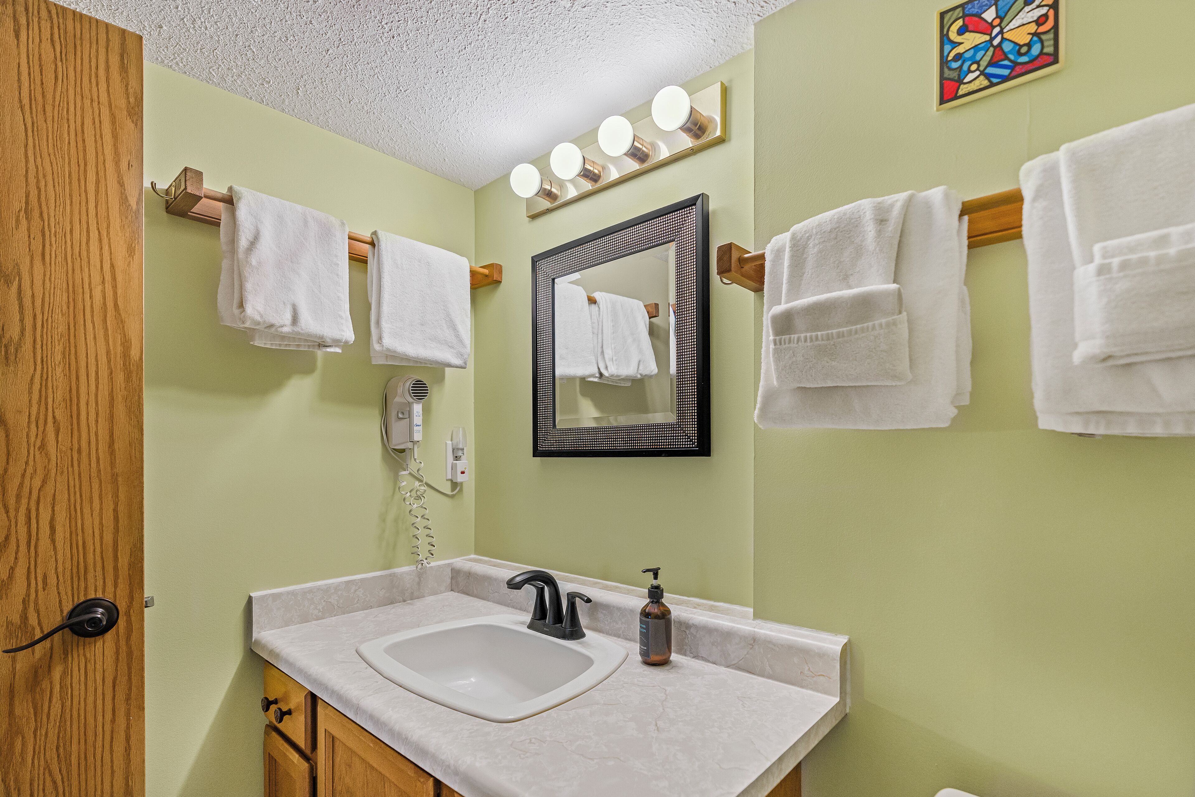 Un bagno con lavandino, specchio e diversi asciugamani appesi.
