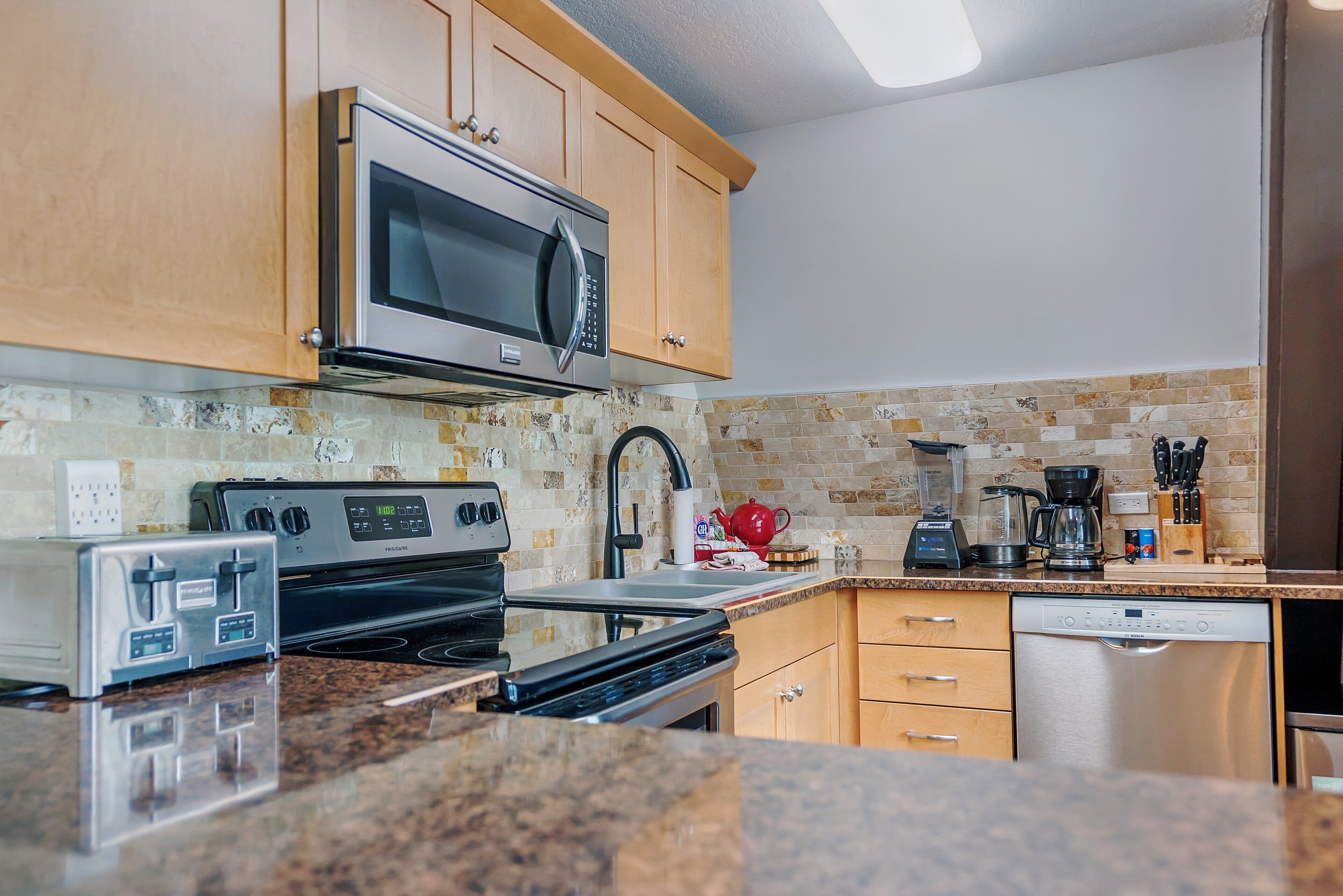 A kitchen with wooden cabinets, a microwave, a toaster, a coffee maker, and a dishwasher.