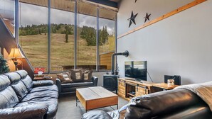 A modern living room with leather sofas, a wooden coffee table, a TV, and a fireplace. - Cozy Ski-In/Out Retreat with Hot Tub & BBQ (Vernon)