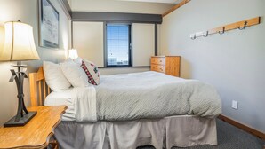 A neatly arranged bedroom with a bed, bedside table, lamp, and a window with blinds. - Charming 2-Bedroom Suite – Perfect for Families & Groups (Vernon)