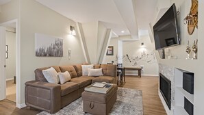 Una sala de estar moderna con un sofá seccional, una chimenea y un televisor de pantalla plana montado en la pared.