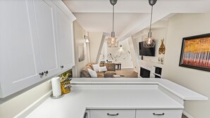 Una cocina moderna con armarios blancos, una encimera y una zona de comedor con sofá y mesa.