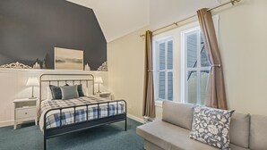 A bedroom with a bed, bedside tables, a window with curtains, a sofa, and a wall-mounted picture.
