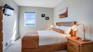 A bedroom with a bed, bedside table, lamp, and a painting on the wall. - Bright & Spacious Property w/ Fireplace & Hot Tub - Sleeps 13 (Vernon)