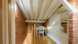 A narrow hallway with exposed wooden beams, a brick wall, and a white door.