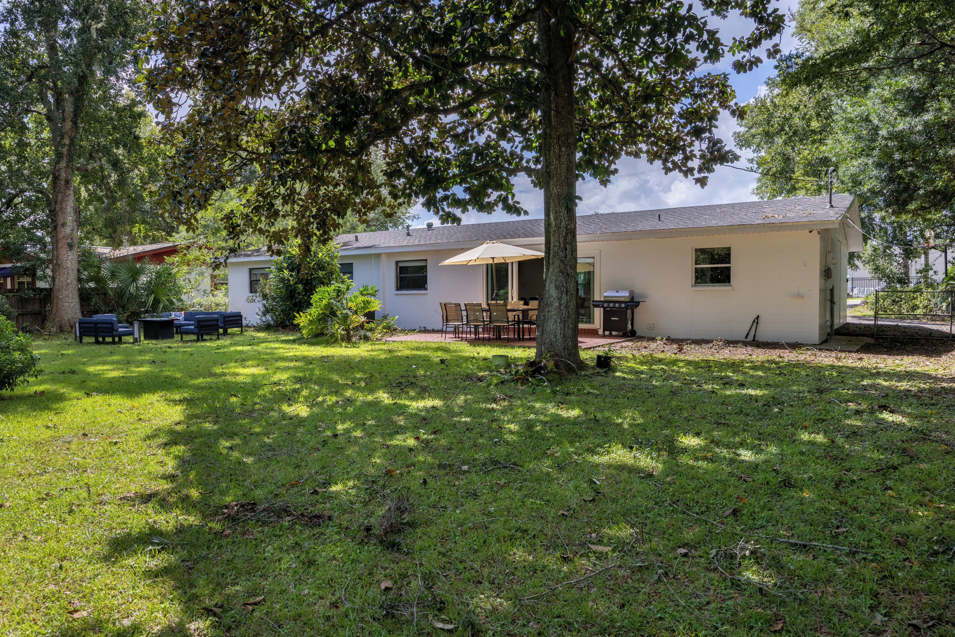 A residential property with a covered patio, outdoor seating, and a lawn.