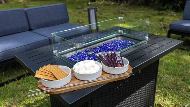 A glass-top table with snacks and marshmallows, set outdoors with a sofa in the background. - 4BR Charm, 5 min to UF, Firetable, Big backyard, King Bed, Games, BBQ, Joy (Gainesville)