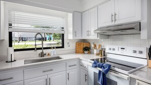A modern kitchen with white cabinets, a stainless steel sink, and a built-in oven. - 4BR Charm, 5 min to UF, Firetable, Big backyard, King Bed, Games, BBQ, Joy (Gainesville)