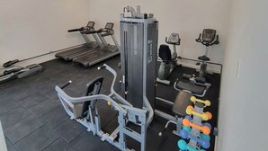 Une salle de sport équipée de tapis de course, d’appareils de musculation et d’haltères.