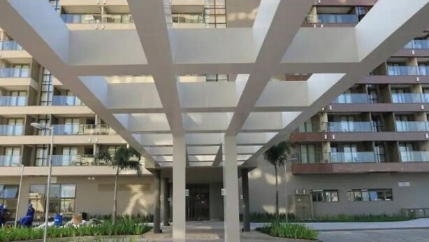 Un immeuble à plusieurs étages doté de balcons, d’une entrée couverte et d’un espace paysager agrémenté de plantes.