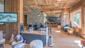 Un vaste espace de vie doté d’un plafond en bois, d’un mur en pierre et d’un coin salon confortable.