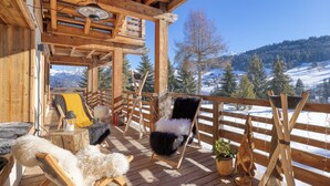 Une terrasse en bois offrant une vue sur des montagnes et des arbres couverts de neige.