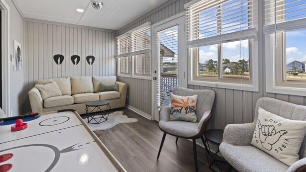 A cozy living room with a sofa, armchairs, a coffee table, and a shuffleboard table. - Rhythm Retreat  | Bar, Patio & Space for 10 (Myrtle Beach)