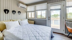 A bedroom with a bed, a chair, a door, and windows. - Rhythm Retreat  | Bar, Patio & Space for 10 (Myrtle Beach)