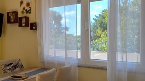A room with a large window, a sofa, a small table, and wall-mounted decorations. - Stunning apartment in Zaton (Zaton)
