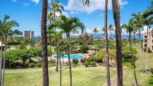 A resort with a swimming pool surrounded by palm trees and a view of the ocean. - Luxurious and Spacious 2BD Kaanapali Condo (Lahaina)