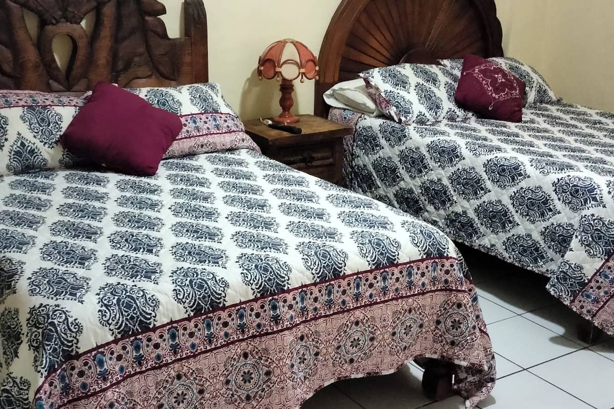 A room with two beds, each with patterned bedding and a wooden headboard.