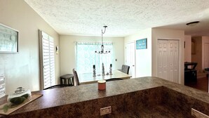 A kitchen with a granite countertop, a chandelier, a dining area with a table and chairs, and a view of the beach through a window. - 3-bedroom, 2.5-bathroom, sleeps 10 people with heated pool and elevator. (Murrells Inlet)