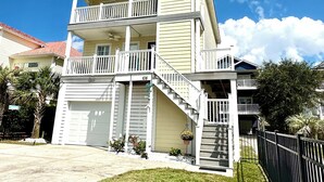 A two-story house with a front porch, a garage, and a staircase leading to the upper floor. - 3-bedroom, 2.5-bathroom, sleeps 10 people with heated pool and elevator. (Murrells Inlet)