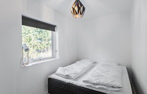 A bedroom with a bed, a window, and a hanging light fixture.