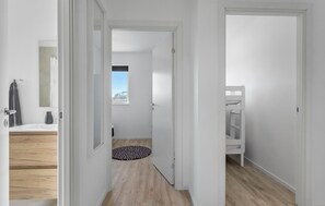 A hallway with a wooden floor, a white door, and a small window.