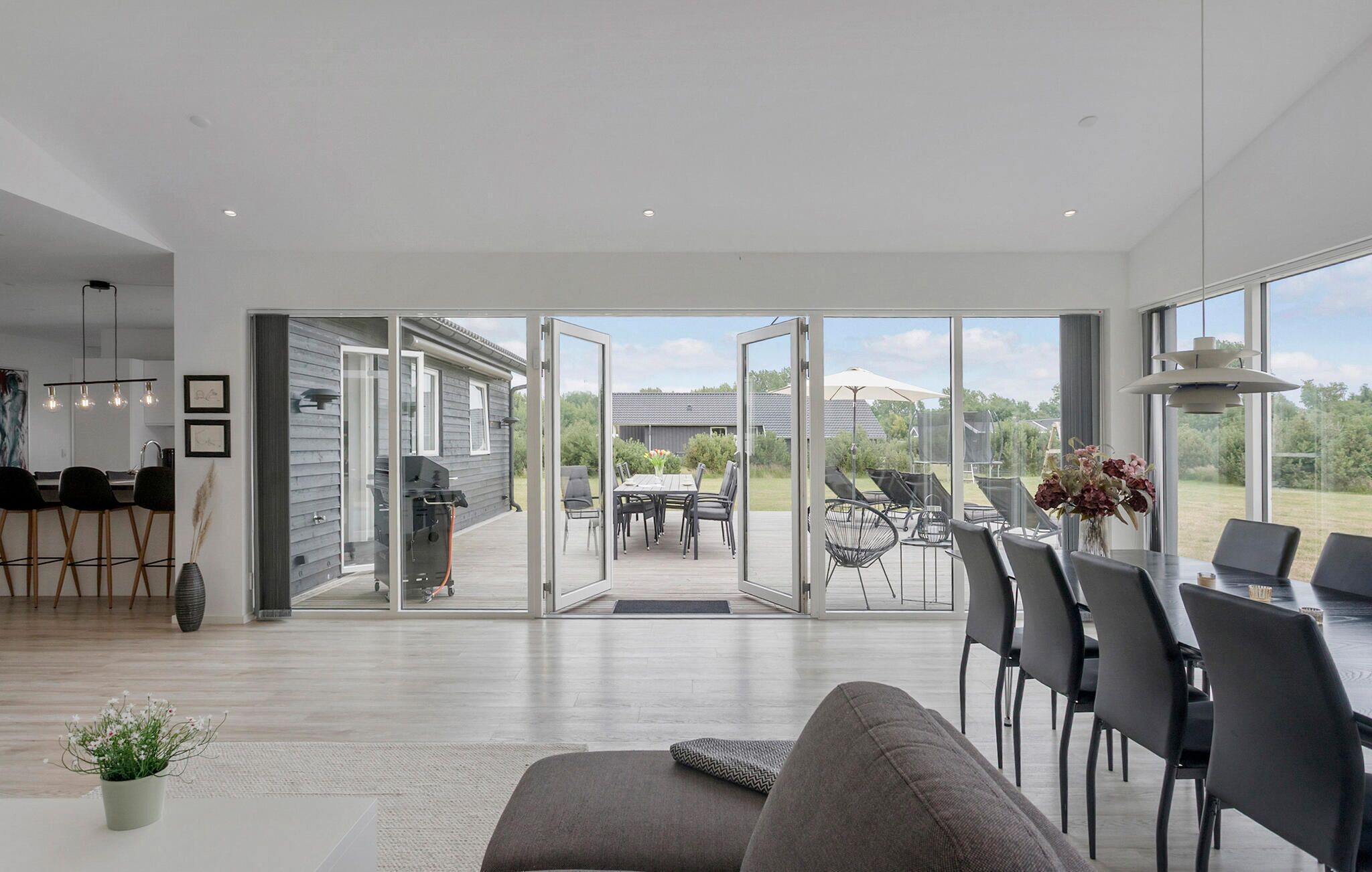 Een modern interieur met een eethoek, een bank en uitzicht door glazen deuren op een terras.