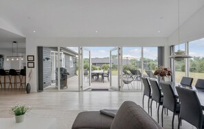 A modern interior with a dining area, a sofa, and a view through glass doors to an outdoor patio. - 5 bedroom cozy home in Væggerløse (Væggerløse)