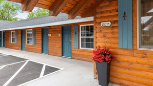A wooden building with a covered entrance, a sign indicating an office, and a planter with red flowers.