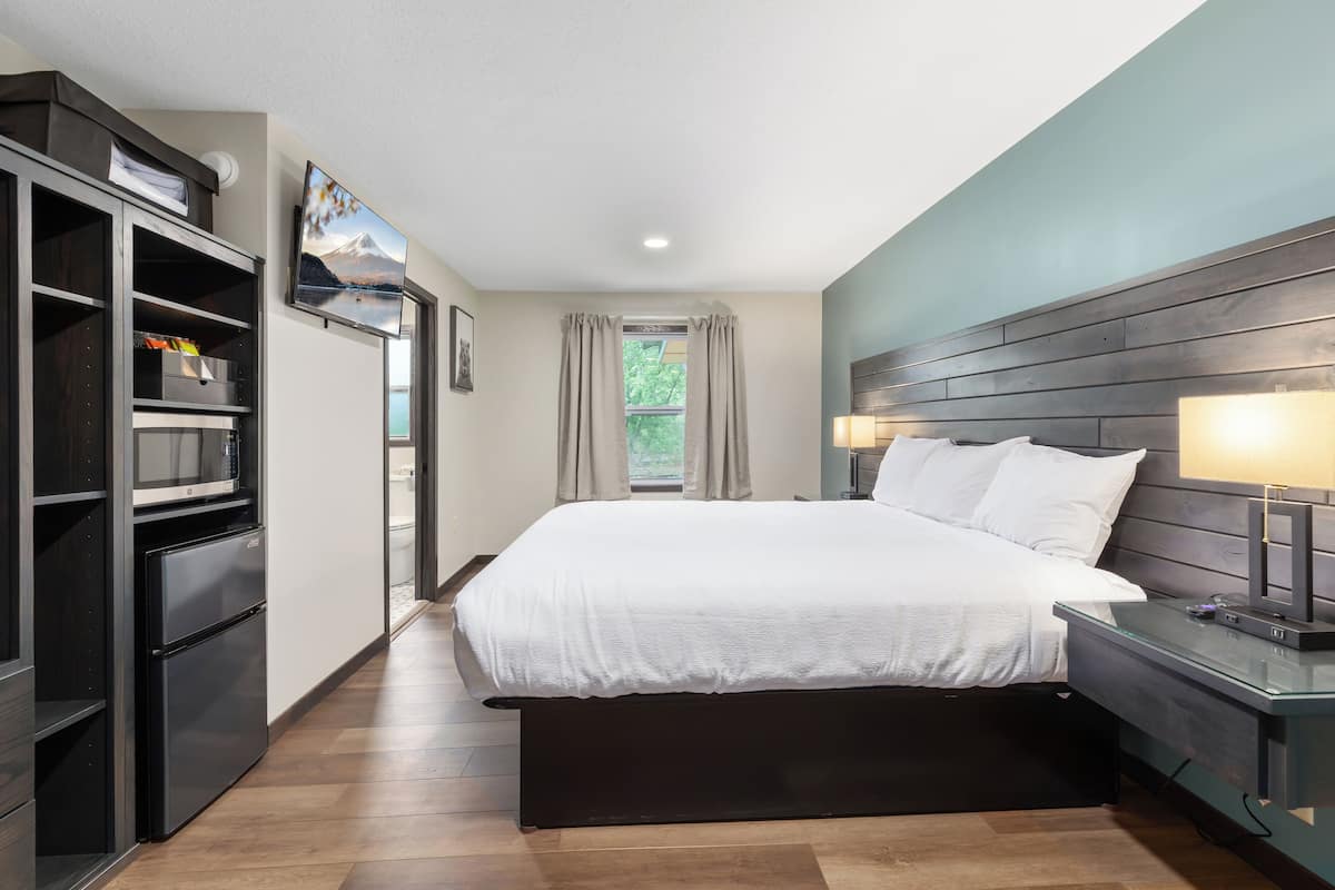 A modern bedroom with a bed, bedside lamps, a TV, and a wardrobe.