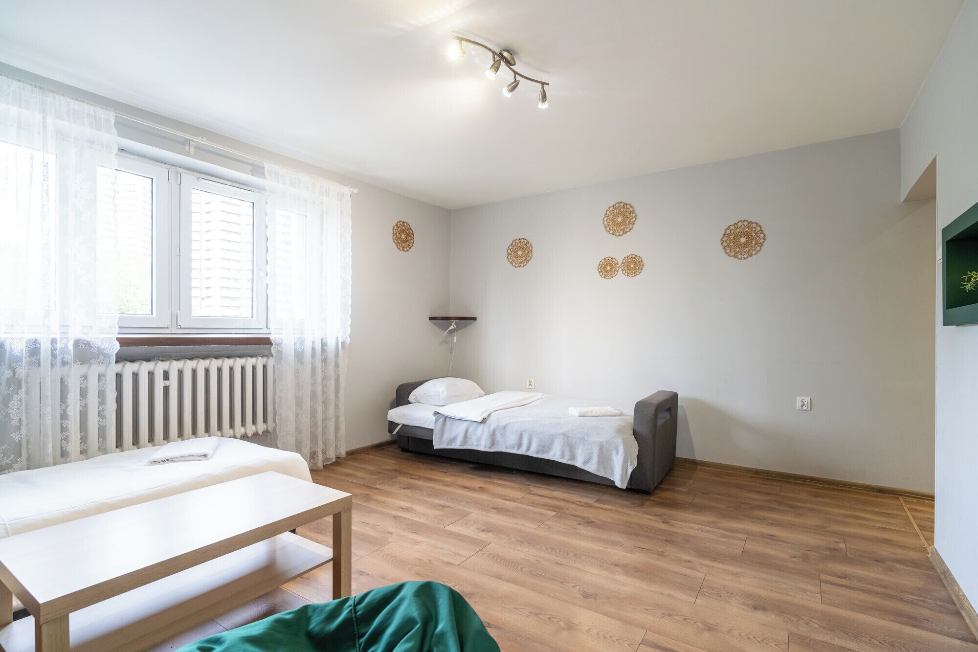 A bedroom with a bed, bedside table, radiator, and decorative wall panels.