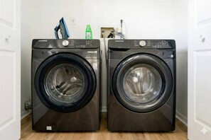 Two front-loading Samsung washing machines in a laundry room with a wooden floor. - Private heated  pool house with mini golf (Kissimmee)