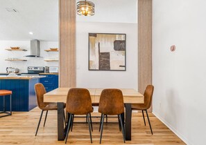 Une cuisine moderne avec des meubles de rangement bleus, une table à manger en bois et quatre chaises marron.
