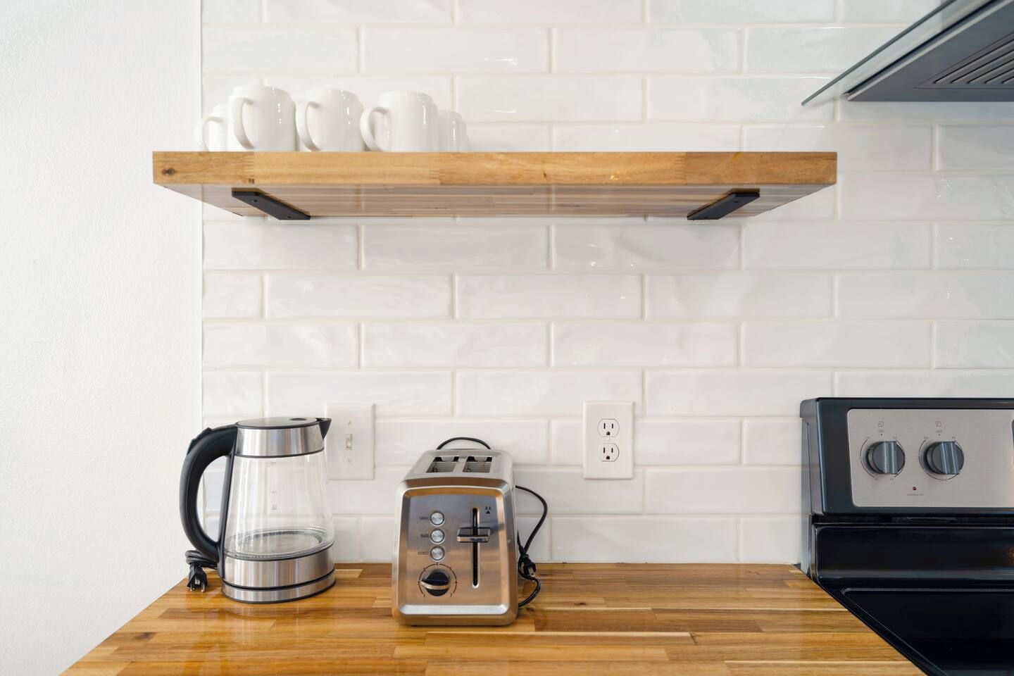 A kitchen with a wooden countertop, a coffee maker, a toaster, and a stove.