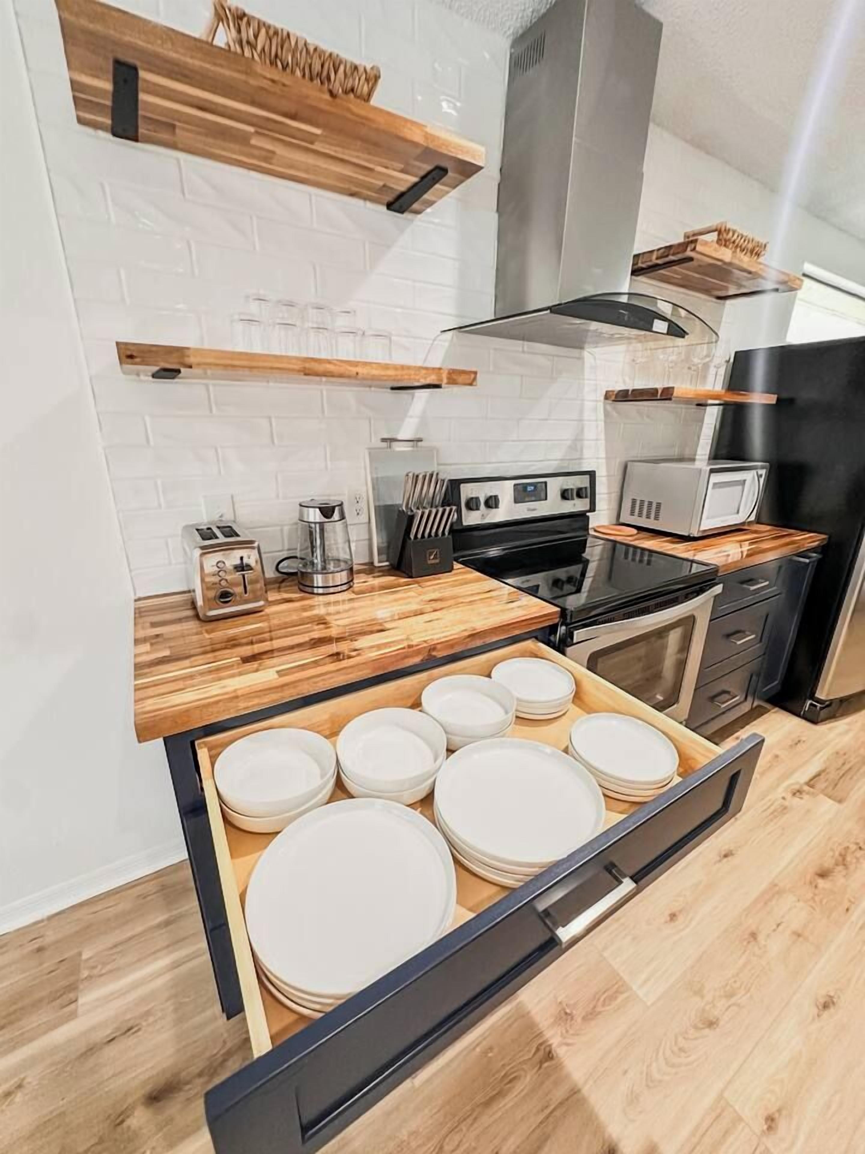 A modern kitchen with wooden countertops, a built-in microwave, and a stainless steel range hood.