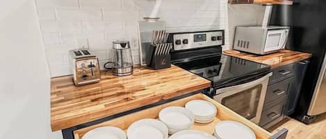 A modern kitchen with wooden countertops, a built-in microwave, and a stainless steel range hood.