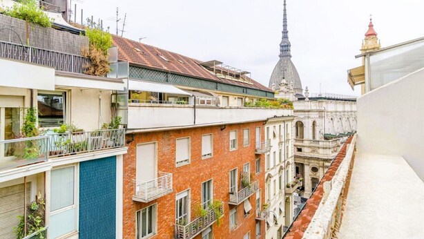 A multi-story building with balconies, a red brick facade, and a view of a tall tower in the background. - GuestHost - Cosy flat with a view of the Mole Antonelliana for 3 people, located on the 5th floor of a period building (WITH LIFT). The building is located in the historic centre of Turin, a few minutes on foot from the Mole Antonelliana and the Egyptian (Torino)