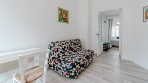 A room with a white sofa, a white chair, a wooden table, and a door leading to another room. - GuestHost - Cosy flat with a view of the Mole Antonelliana for 3 people, located on the 5th floor of a period building (WITH LIFT). The building is located in the historic centre of Turin, a few minutes on foot from the Mole Antonelliana and the Egyptian (Torino)